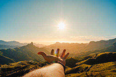 Low section of person on mountain against sky during sunset
