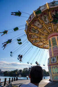 Low angle view of people on amusement park ride against sky