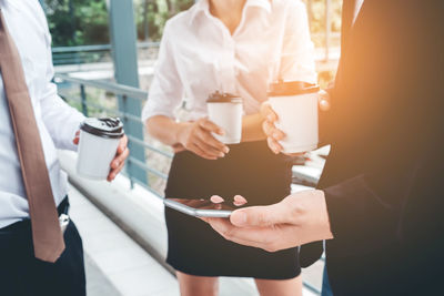 Midsection of business colleagues holding disposable cups