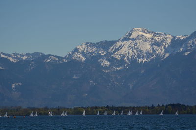 Scenic view of lake and mountains against clear blue sky