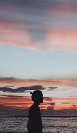 Silhouette man on beach against sky during sunset