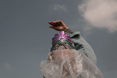 Low angle view of woman with plastic on face against sky