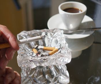 Close-up of hand holding cigarette over ashtray