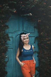 Portrait of smiling young woman standing against plants