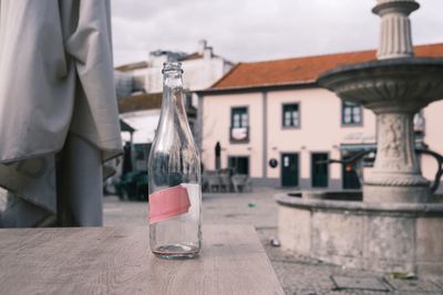 Glass bottle on table against city