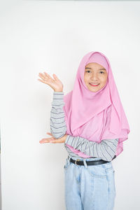 Portrait of a smiling girl standing against pink white background