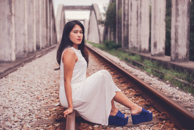 Portrait of woman sitting on railroad track