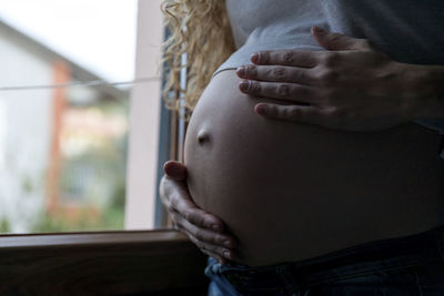 Young pregnant woman touching abdomen at home