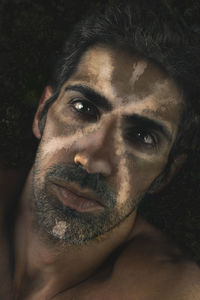 Close-up portrait of man with face paint against black background