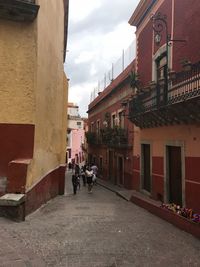 People walking on footpath amidst buildings in city