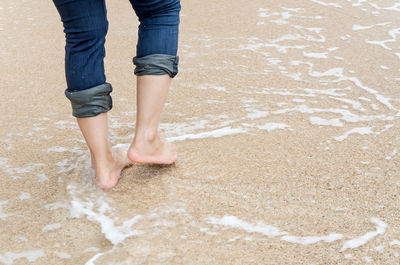 Low section of woman walking on shore at beach