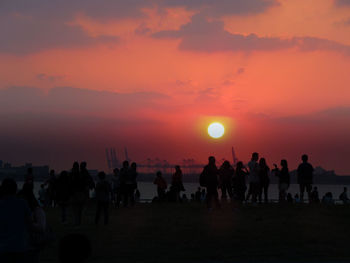 Silhouette people at beach against sky during sunset