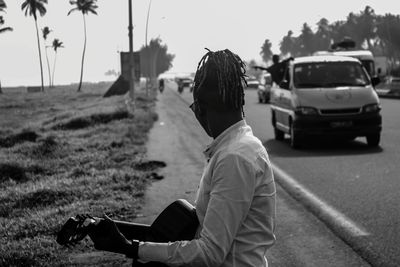 Side view of woman playing guitar while standing on road