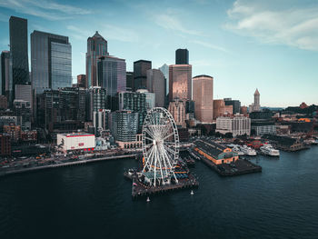 Modern buildings by river against sky in city