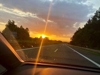 Road seen through car windshield during sunset