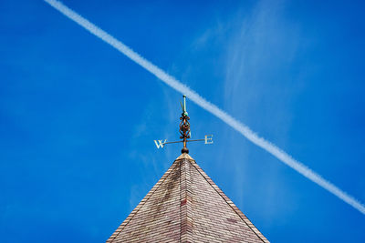 Low angle view of building against blue sky with contrail