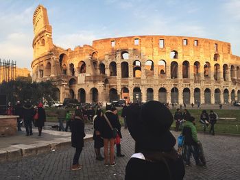 Tourists in front of coliseum against sky