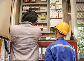 Rear view of man using electric control box