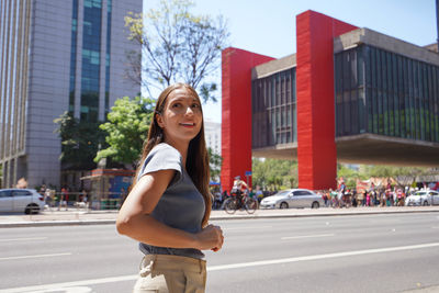 Portrait of young woman standing on street in city