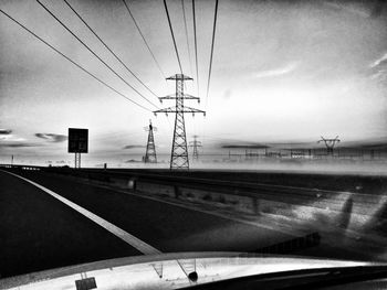 Power lines against cloudy sky
