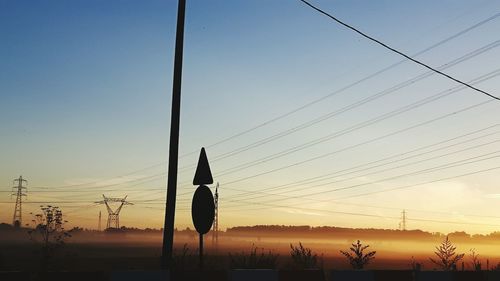 Power line above landscape in foggy weather during sunrise