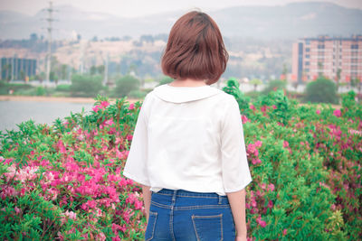 Rear view of woman standing on flowering plants