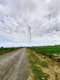 Road amidst field against sky