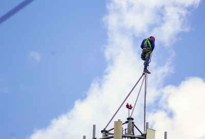 Low angle view of man climbing against sky