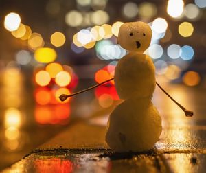 Close-up of snowman on illuminated street at night