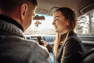 Young trendy couple discussing their route in  car with phones in hand - modern navigation 