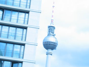 Low angle view of communications tower against cloudy sky