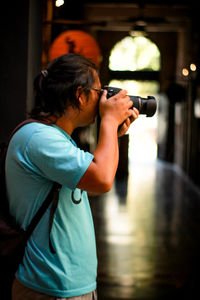 Side view of man photographing with camera while standing outdoors