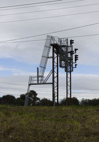 Low angle view of electricity pylon on field against sky