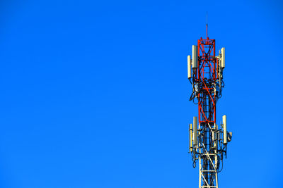 Low angle view of electricity pylon against clear blue sky