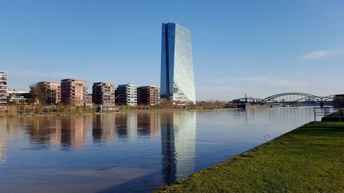 Reflection of modern buildings in city against blue sky