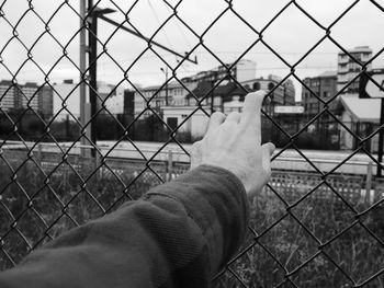 Man seen through chainlink fence against sky