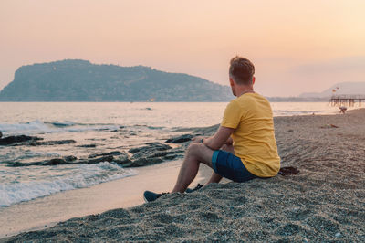 Rear view of woman sitting on beach