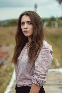 Side view portrait of young woman standing on field