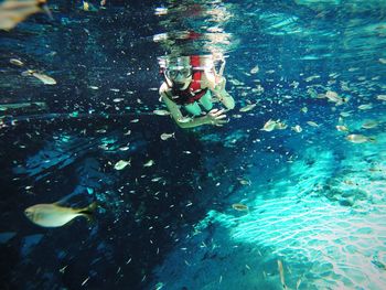 Portrait of woman showing peace sign while snorkeling in sea