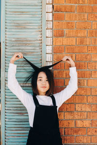 Portrait of woman standing against wall