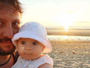 Man and baby on beach at sunset