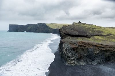 Rock formations on shore against sky