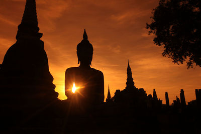 Silhouette statue of temple at sunset
