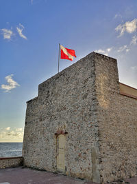 Low angle view of flag on building against sky