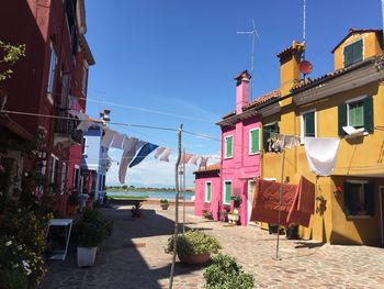 Clothesline hanging amidst buildings against clear blue sky