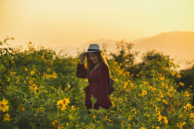 Full length of woman standing on field against orange sky