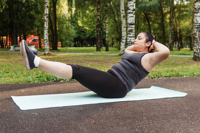 A charming brunette woman plus-size body positive practices sports in nature