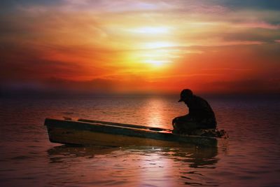 Silhouette person in sea against sky during sunset