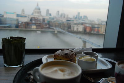 Close-up of coffee on table against buildings in city