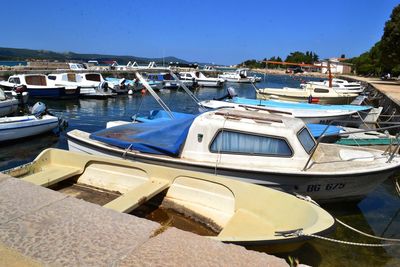 Boats moored at harbor against clear blue sky